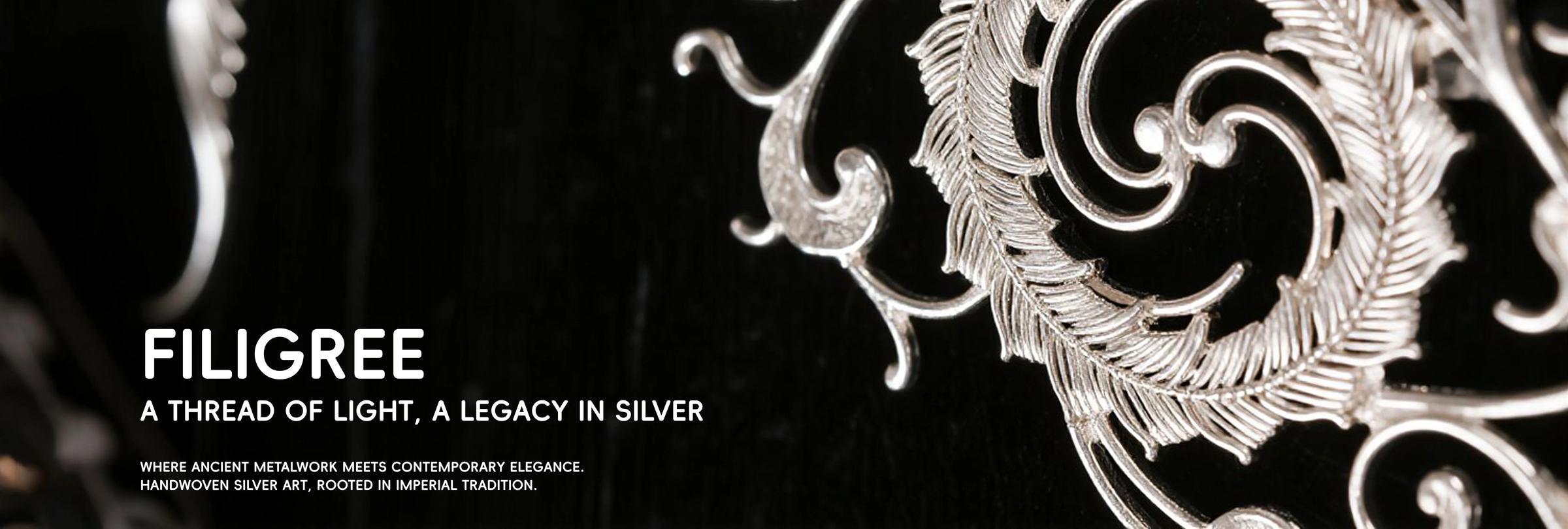 Close-up of silver filigree scrollwork against a black background.